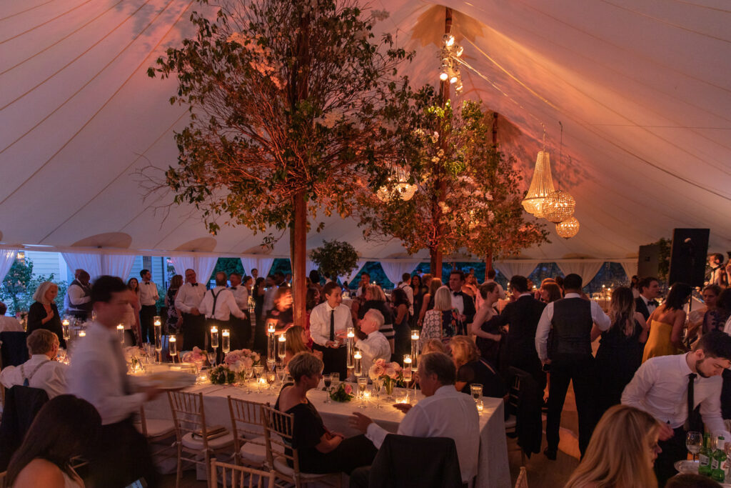 Inside a Greenwich CT tented wedding venue, with guests enjoying the evening light of the reception venue.