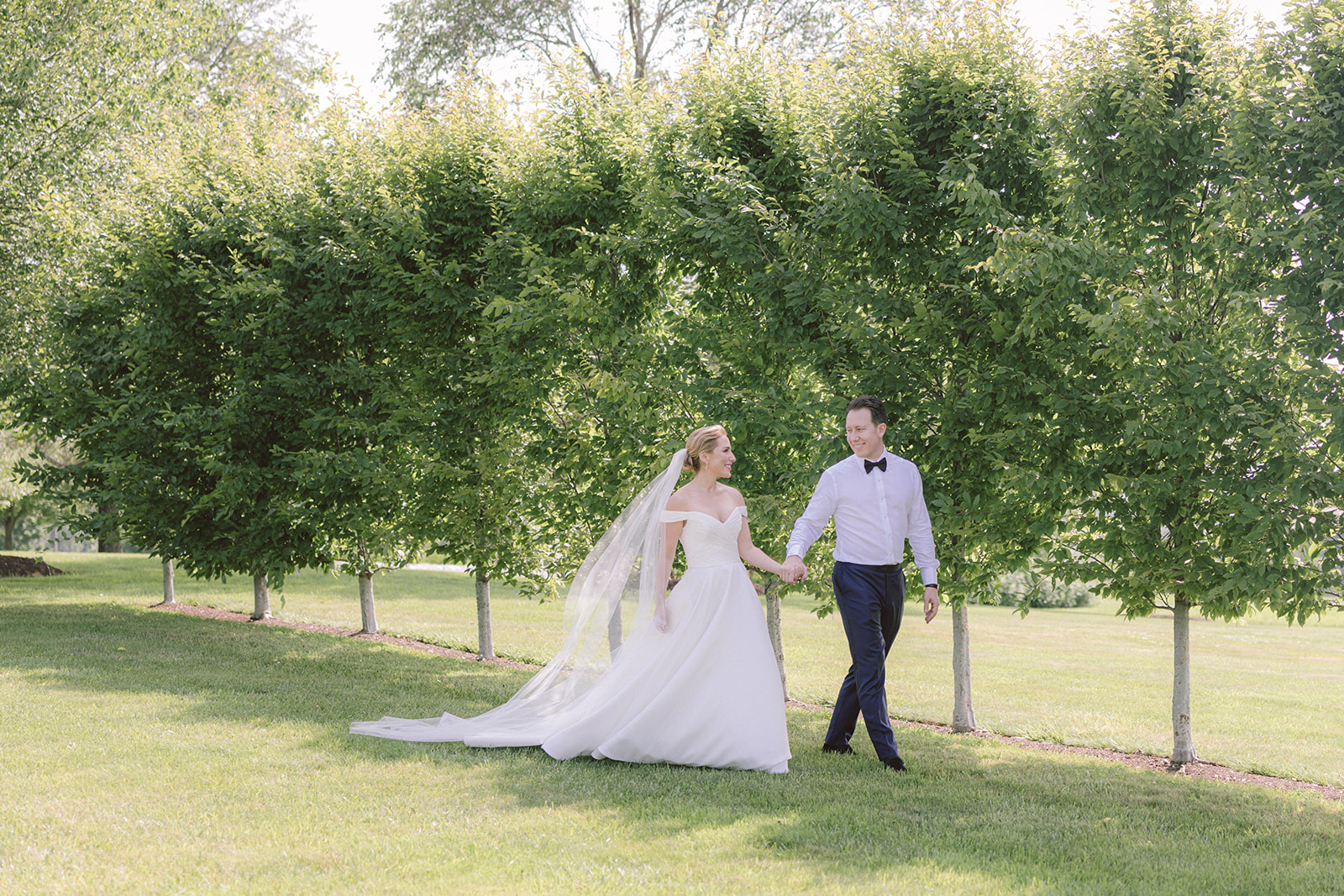 Bride and Groom Holding Hands Walking Across LionRock Farm