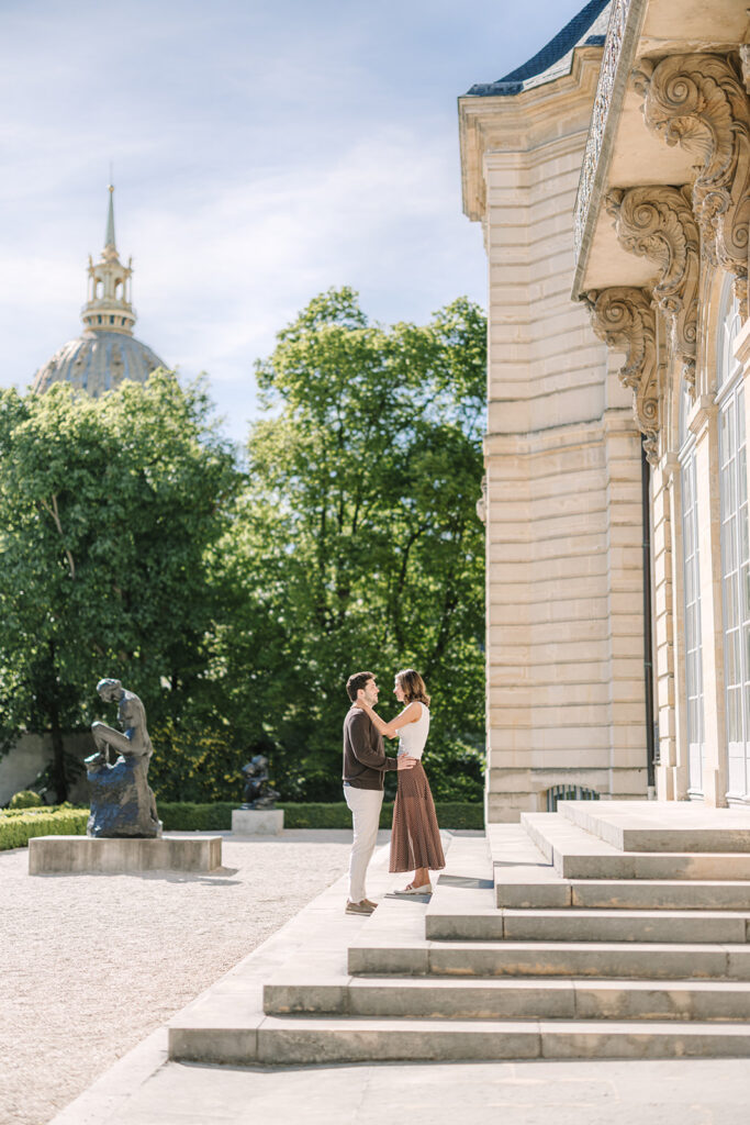 couple standing on the steps of the musee rodin in paris, les invalides in the background