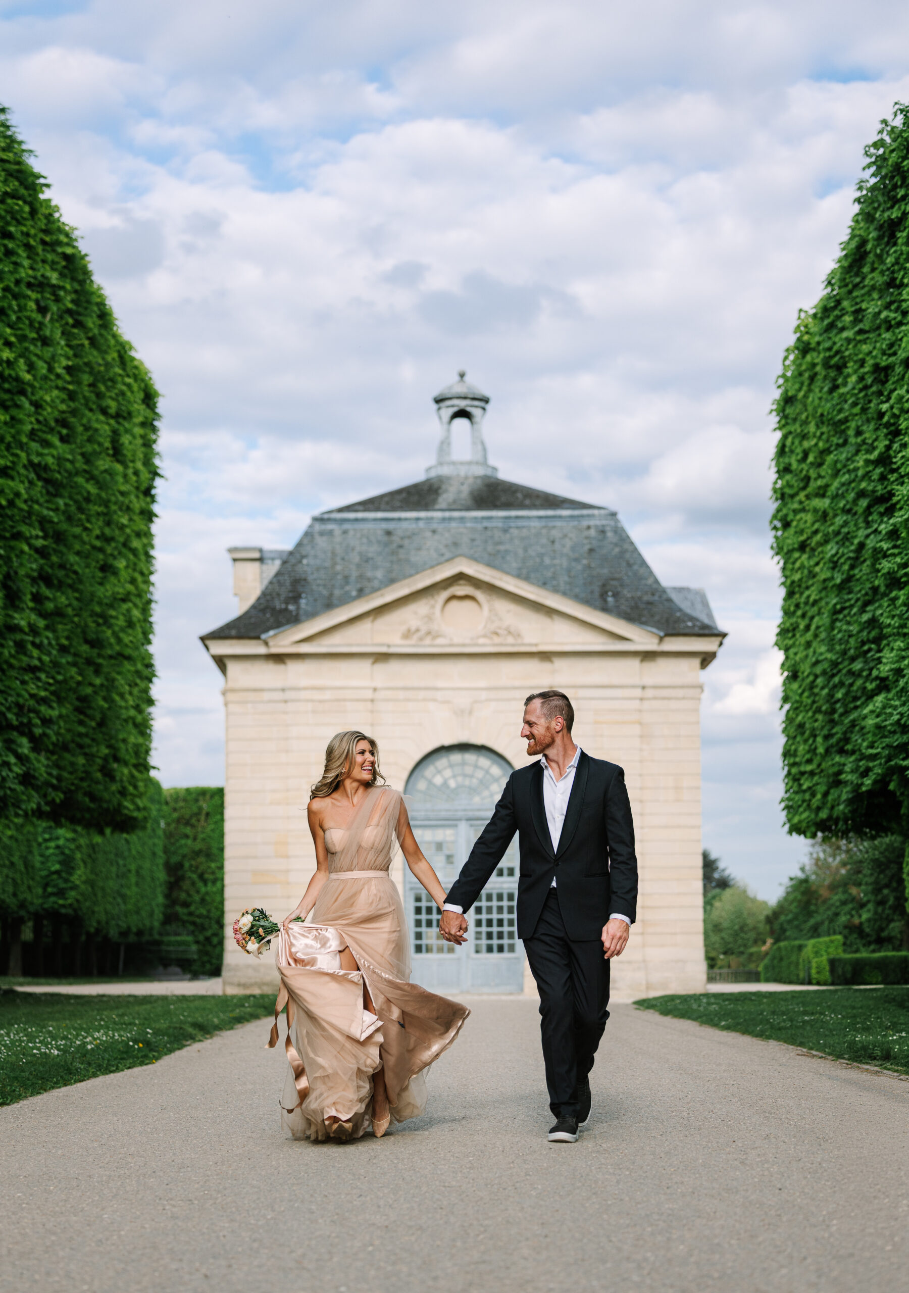 Engaged Couple Hold Hands, Walk Through Gardens in Paris at Château de Sceaux