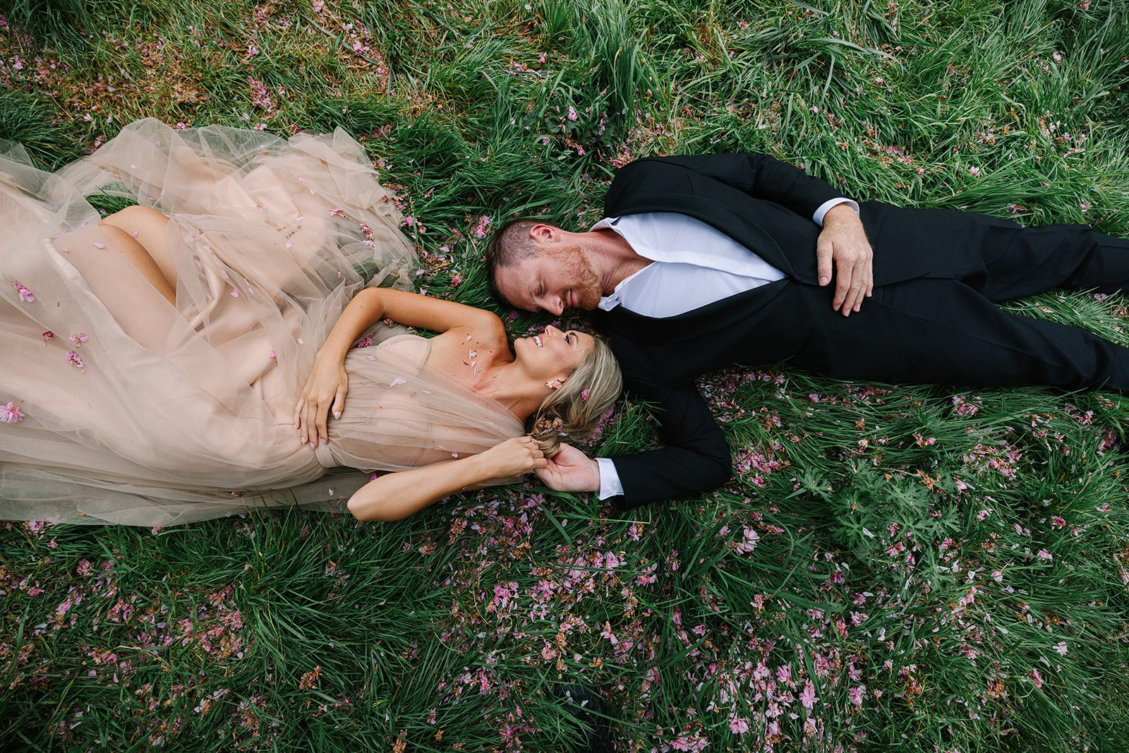 Engaged Couple Lay Lawn of Château de Sceaux, Paris, During Spring, cherry blossoms, engagement session in paris